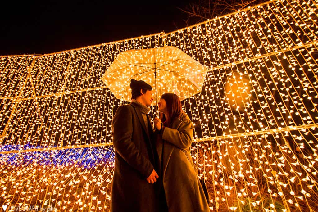 Image of a Japanese couple in front of a Christmas light display
