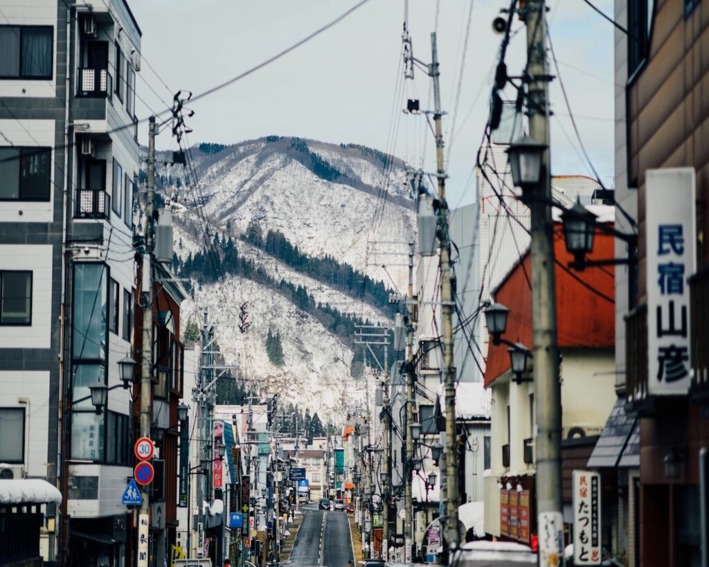 Street in Yuzawa town, Niigata, with a minshuku guesthouse sign and snowy mountains near GALA Yuzawa