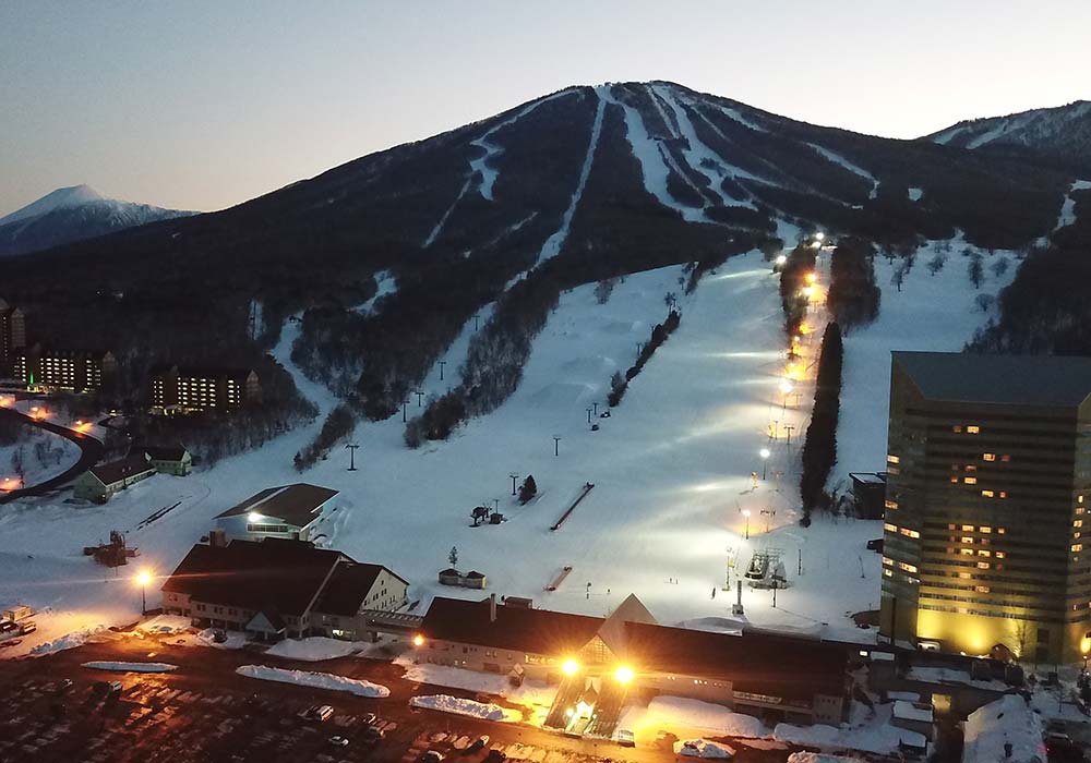 Floodlit ski runs at dusk at Appi Kogen in Iwate, with the resort hotel lit up at the base