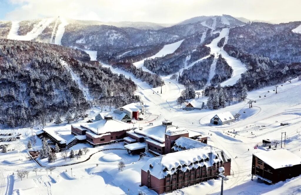 Aerial view of the Kiroro resort base and ski runs cutting through snowy forest near Otaru, Hokkaido