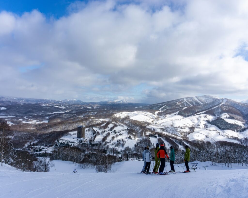 Group of skiers at the top of a run at Rusutsu, looking out over snowy mountains in Hokkaido
