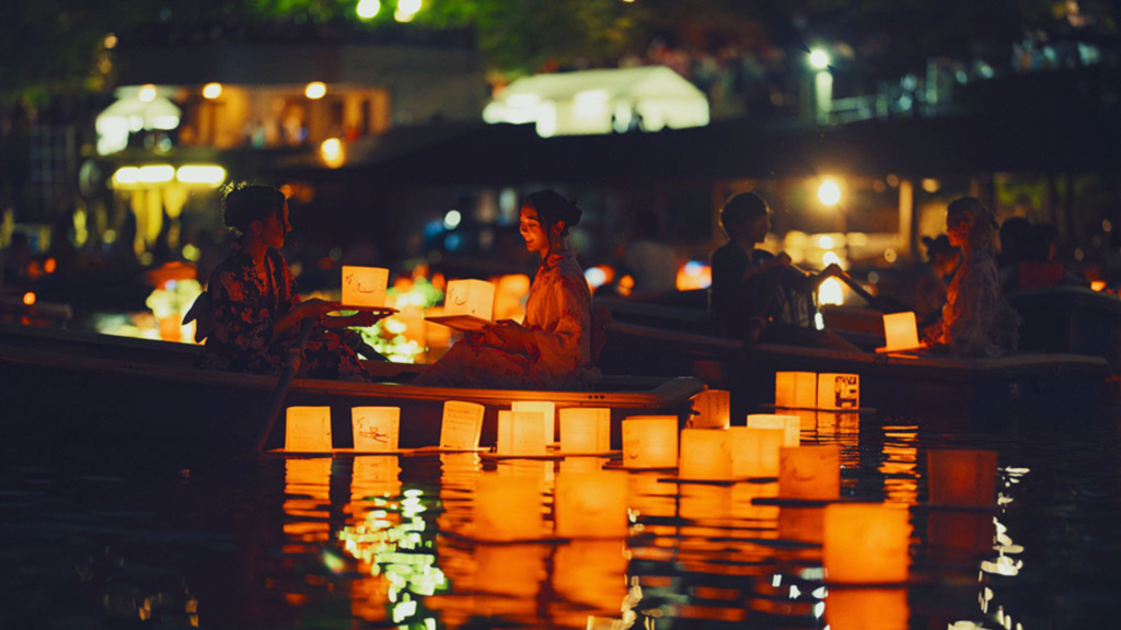 Photo of women on a boat releasing lanterns at the Chiyoda Floating Lanterns Festival, a japanese summer festival