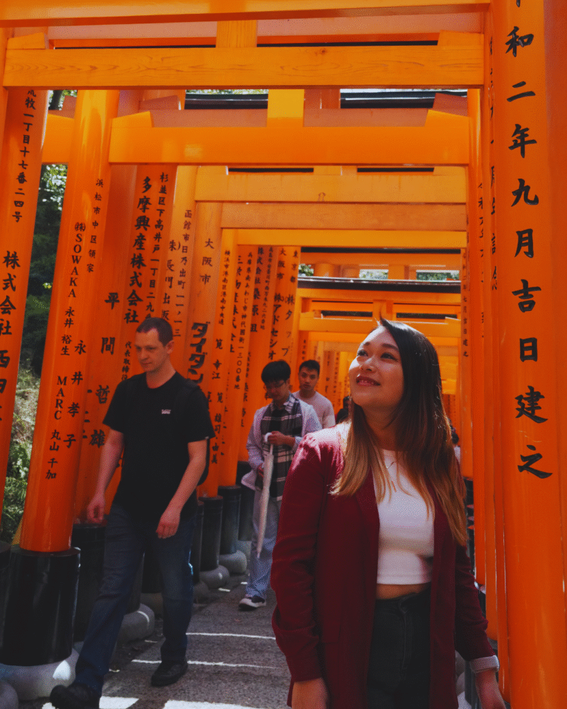 Flip Japan photo of a woman in the torii gates at Fushimi Inari for Osaka vs Tokyo vs Kyoto