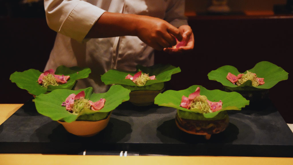 Photo of a chef placing thin slices of Japanese leaf on lily pads at a Michelin-Star restaurant in foodie Japan
