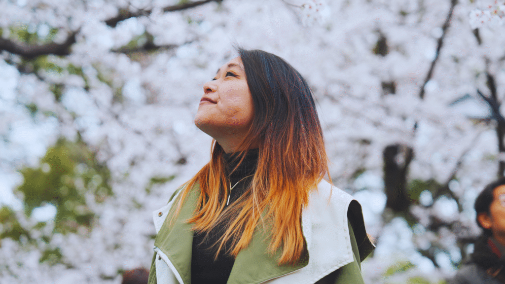Flip Japan photo of a woman standing in front of white cherry blossom trees for Japanese culture