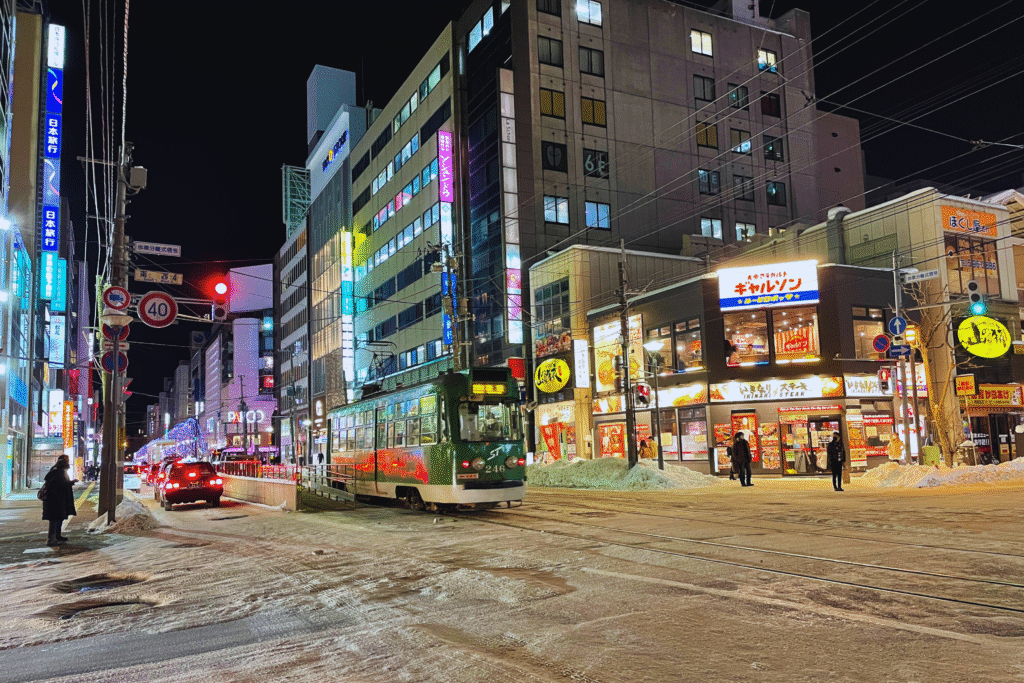 Flip Japan photo of a bus driving down a snowy street at night during winter in Japan