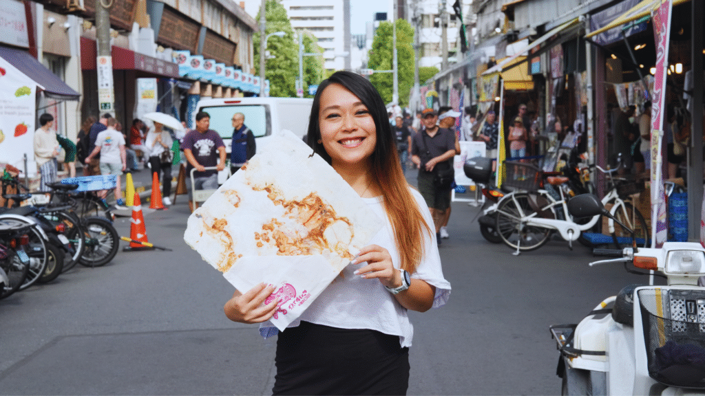 Flip Japan photo of a woman holding a giant cracker in the street of Tsukiji, Chuo, one of the 23 Tokyo Wards
