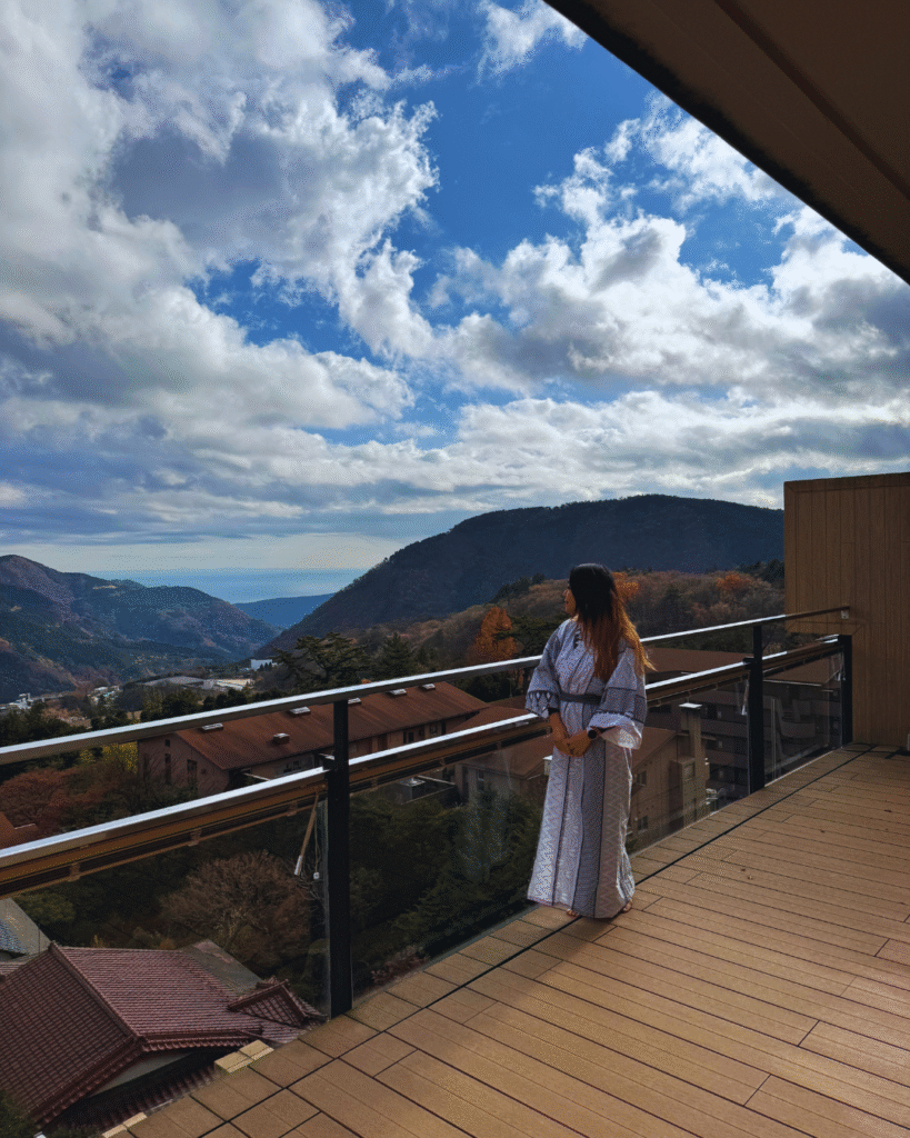 Flip Japan photo of a woman in yukata standing on a balcony overlooking Hakone on a Tokyo winter day trip