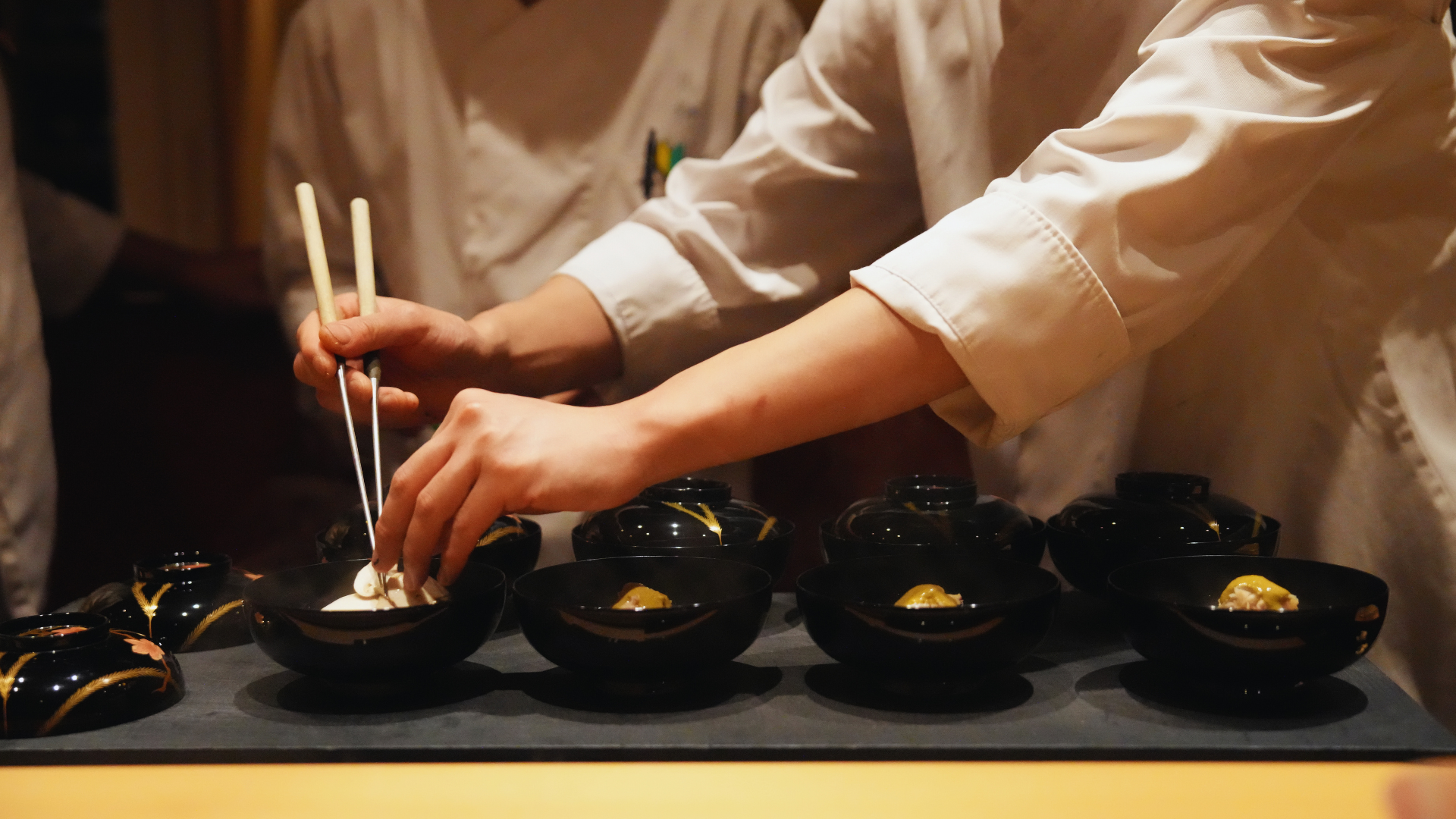 Flip Japan photo of a Japanese chef's hands adding the finishing touches to small plates using chopsticks