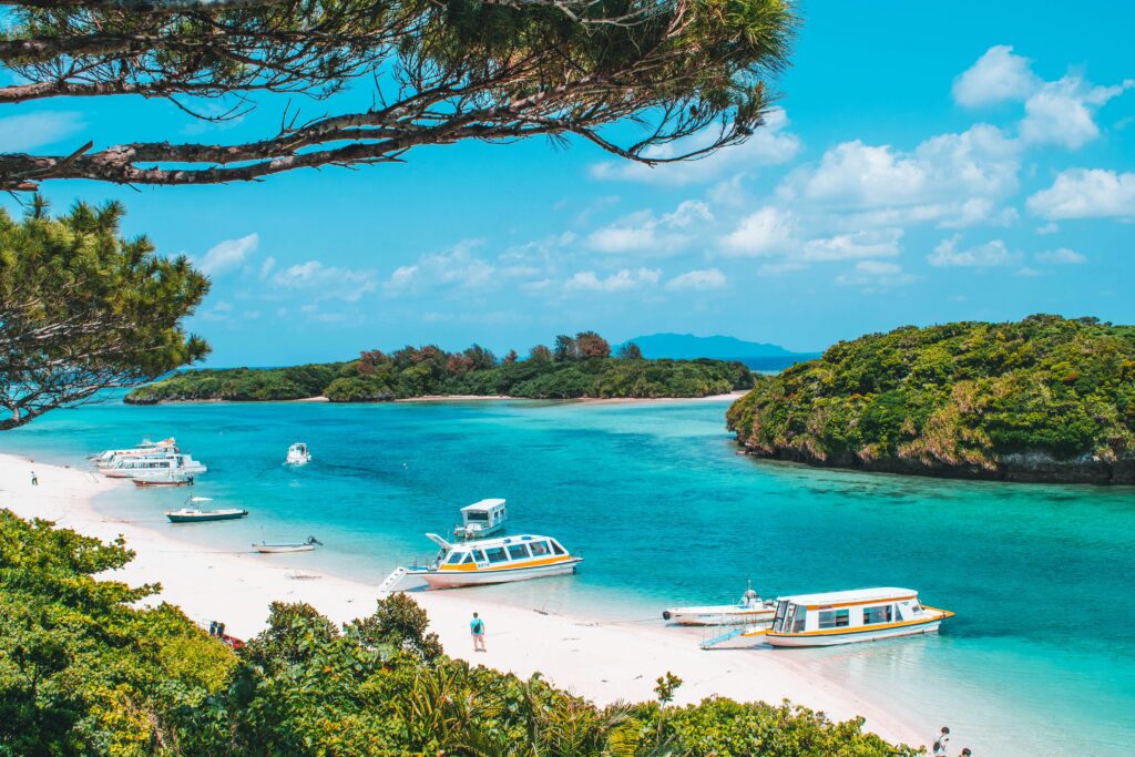 Photo of the beautiful Kabira Bay with bright blue water, surrounded by trees, and with a boat in the water