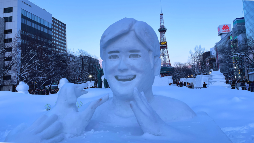 Flip Japan photo of a giant snow sculpture of a man's bust with a dog at a Japanese snow festival