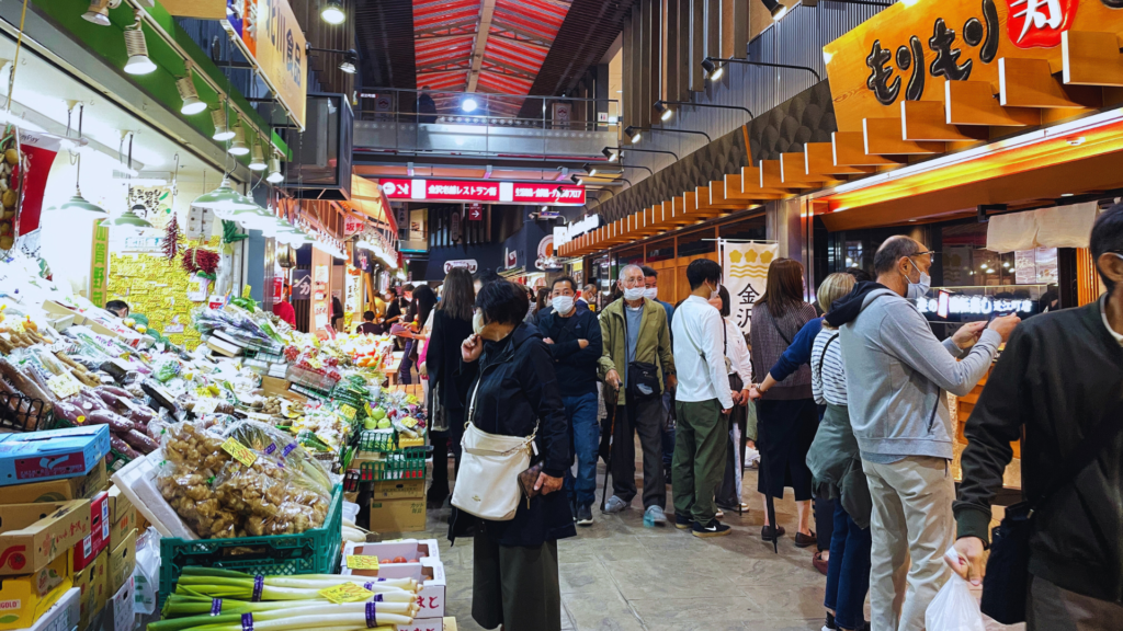 Flip Japan photo of the inside of Omicho Market with stalls selling vegetables and restaurants on either side