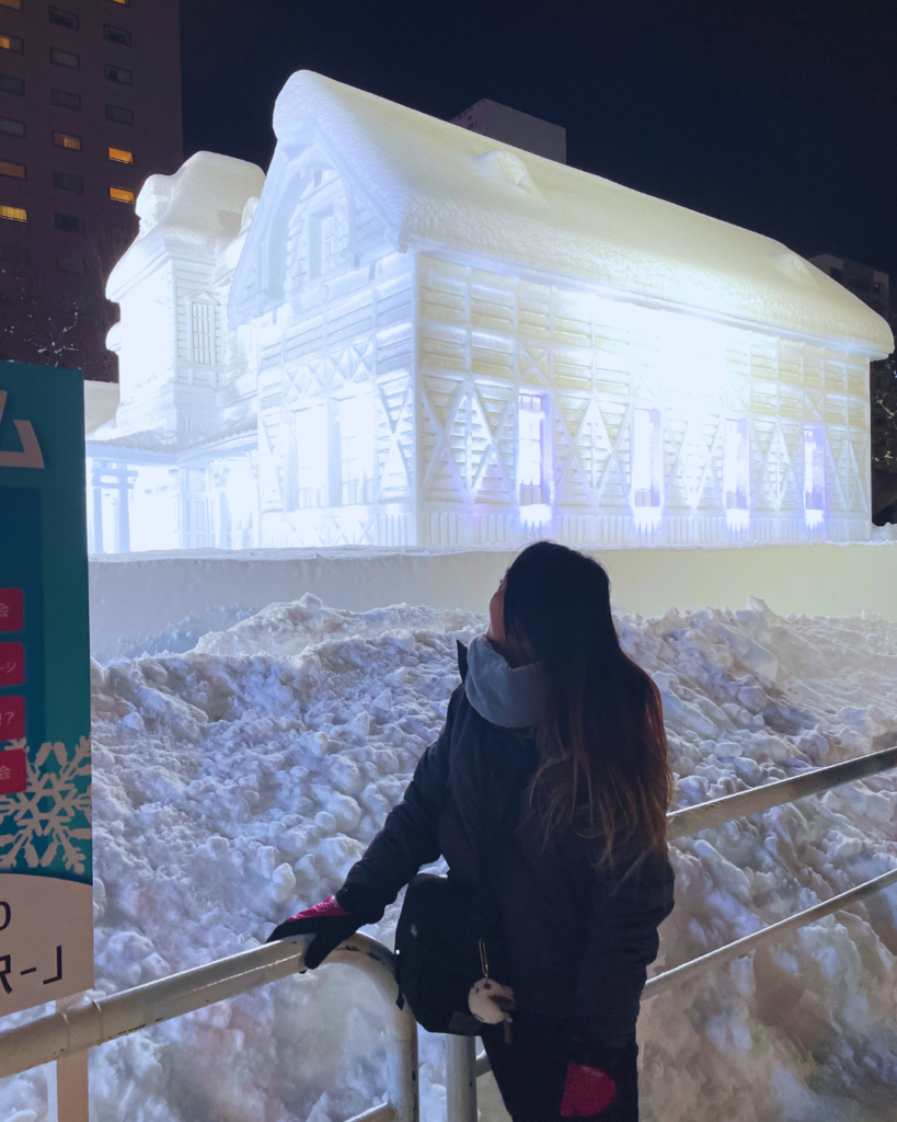 Flip Japan photo of Venese standing in front of a snow sculpture of a large building