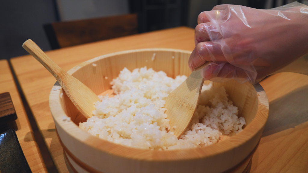 Flip Japan photo of a hand mixing rice as part of a sushi making experience in Japan