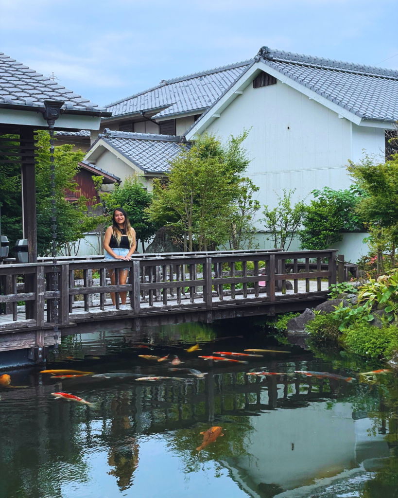 Flip Japan photo of Venese standing on a bridge over a pond with koi fish in Shimabara