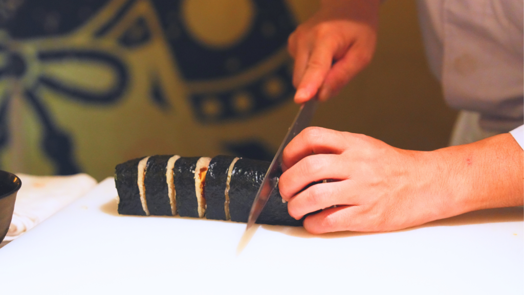 Flip Japan photo of a close up of hands cutting a maki roll for a sushi making class