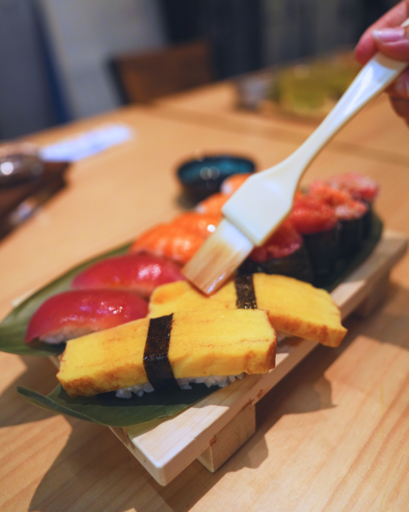 Flip Japan photo of a close up of someone adding glaze to tamagoyaki sushi