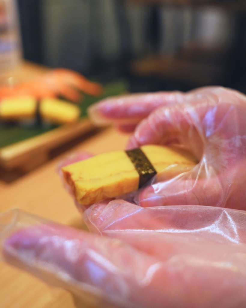 Flip Japan photo of a close up of hands making a tamagoyaki nigiri