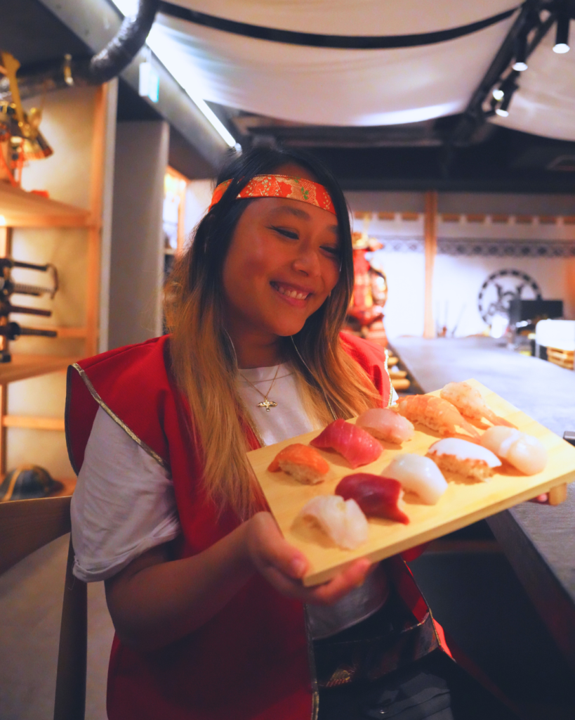 Flip Japan photo of Venese holding a plate of handmade nigiri sushi