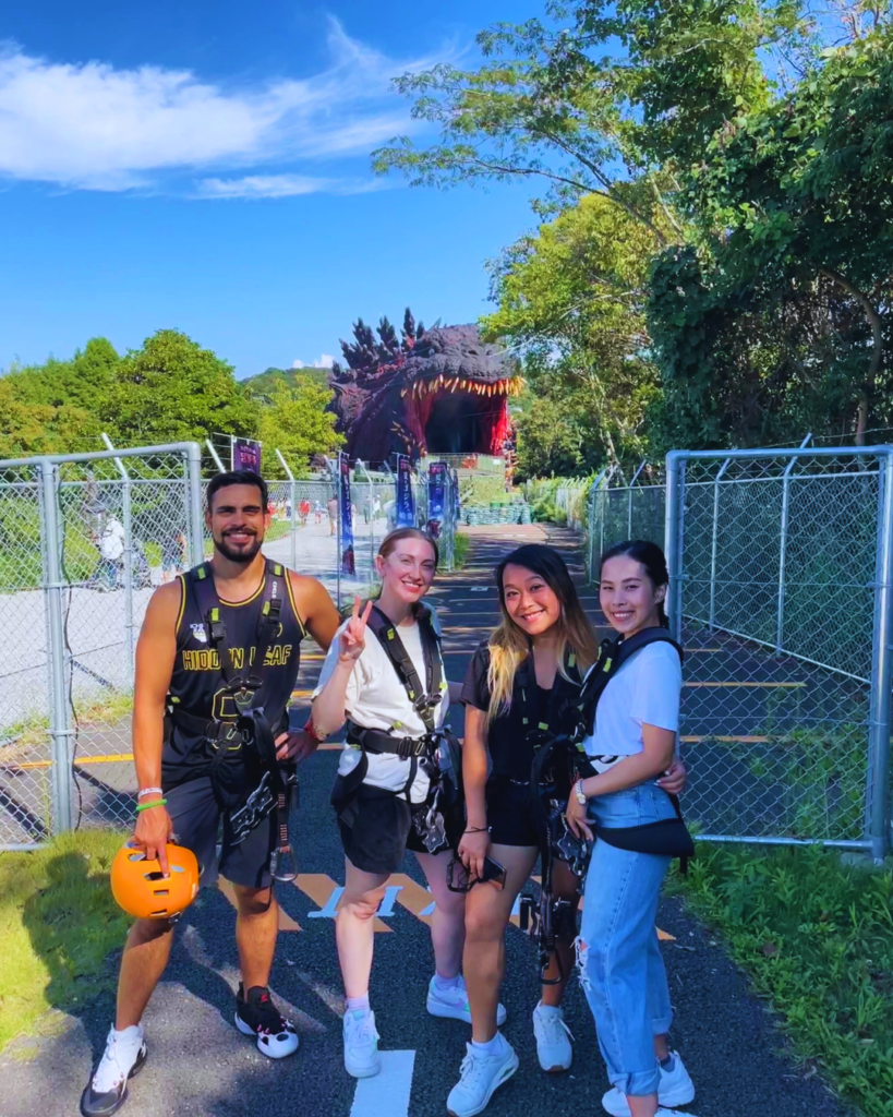 Flip Japan photo of Venese and friends wearing harnesses in front of the Godzilla zipline at Nijigen no Mori
