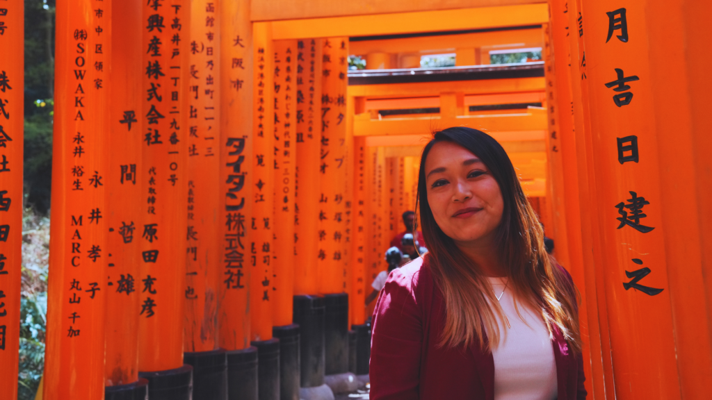 Flip Japan photo of Venese standing under the tunnel of torii gates in Kyoto as a Japan bucket list item