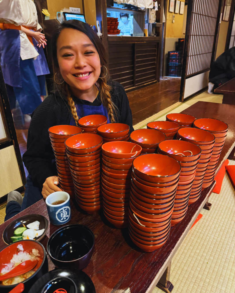 Flip Japan photo of Venese sitting behind a pile of soba bowls in Morioka