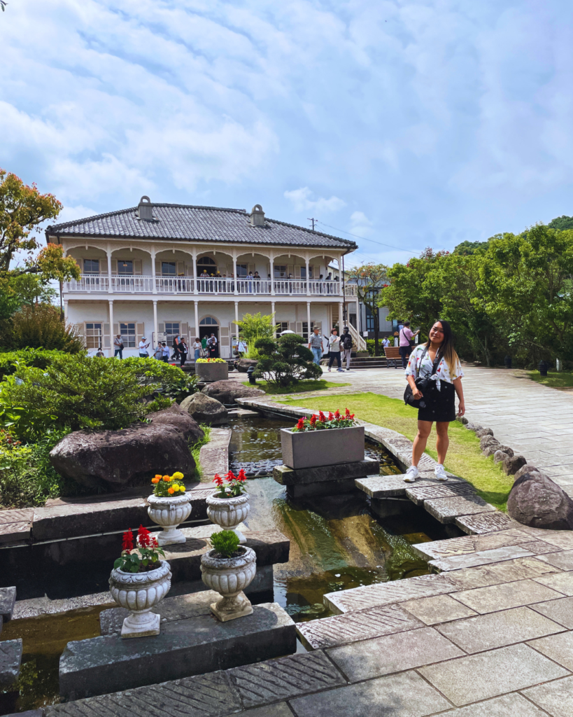 Flip Japan photo of a large western style house in Glover Gardens with Venese standing in front