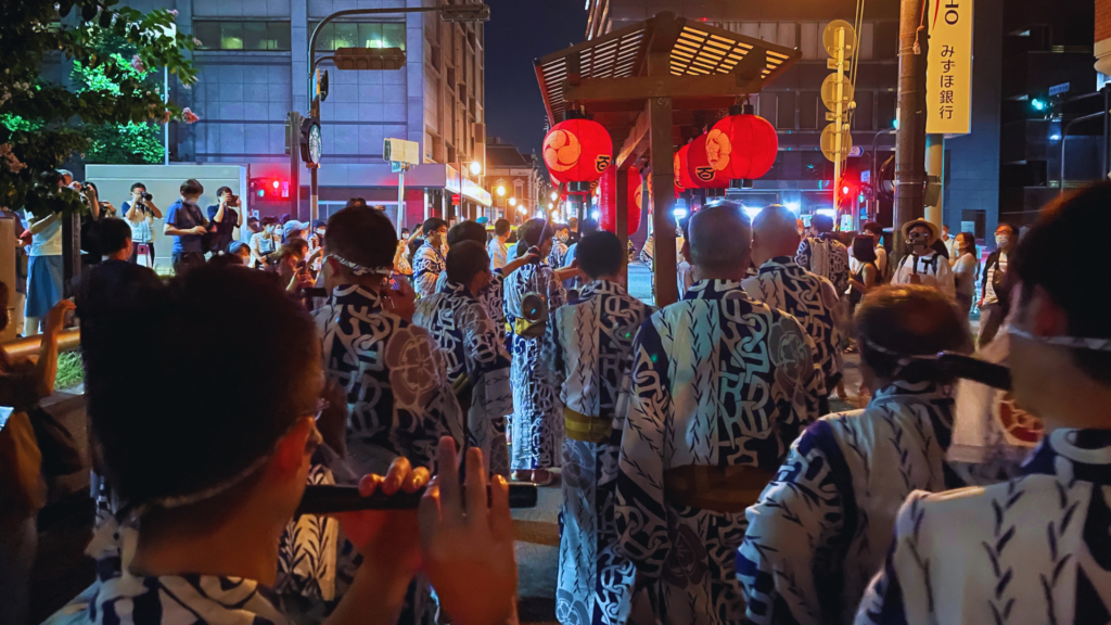 Flip Japan photo of people wearing yukata and standing under lanterns at night to celebrate Yoiyama during Gion Matsuri in Kyoto
