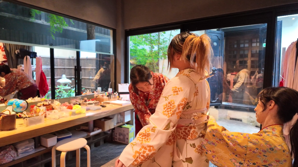 Two practised staff dress the participant in a kimono