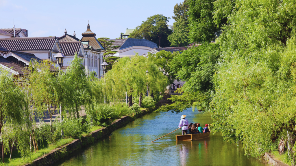 Flip Japan photo of the river canal in Kurashiki with a traditional rowboat travelling down it