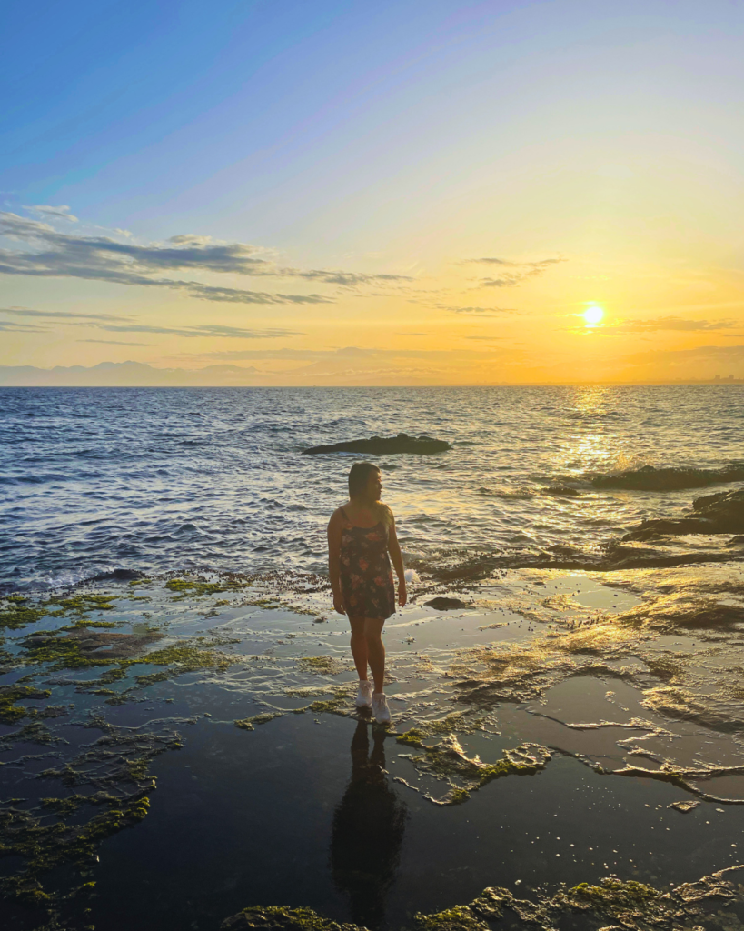 Flip Japan photo of a sunset off the coast of Enoshima. Venese stands in the water as the sun sets behind.