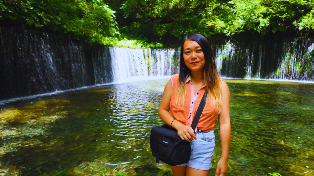 Flip Japan photo of Venese standing in front of a waterfall in a forest in Karuizawa