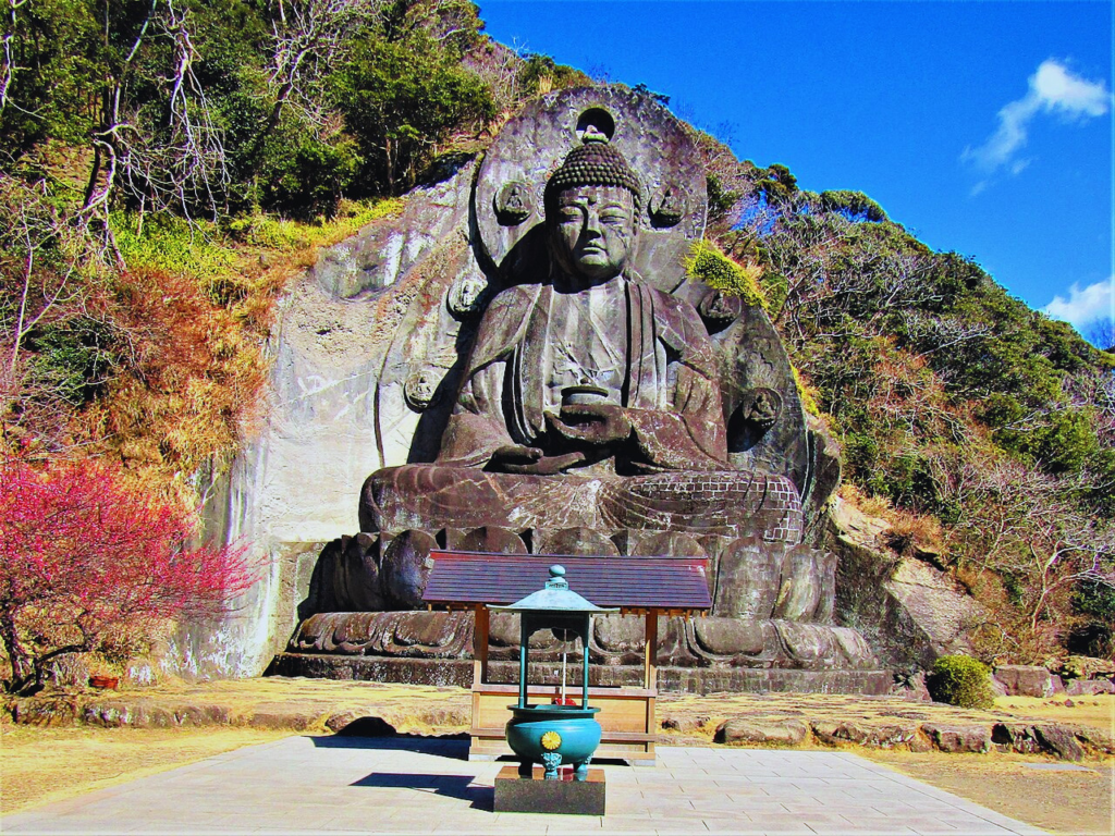 The stone-carved giant Buddha (Nihon-ji Daibutsu) in Chiba is built into the mountain slope with red maples and autumn colours surrounding it.