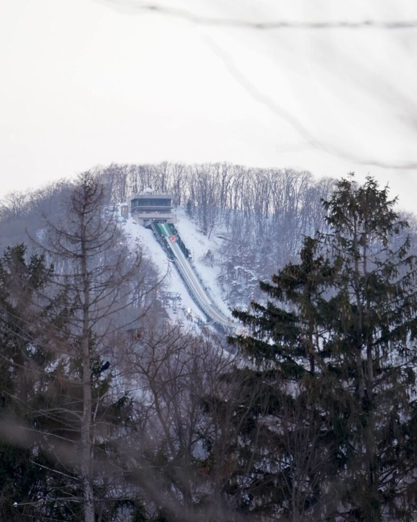 Okurayama Ski Jump Stadium on a snowy mountain in Sapporo, Japan, seen through the trees