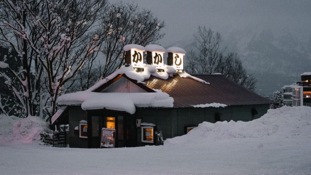 Snow-covered Kakashi izakaya lit up at dusk in Niseko, a cosy dinner spot and one of the things to do in Niseko besides skiing